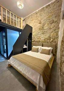 una camera da letto con un letto grande con un muro di pietra di Luvenza Hotel Alaçatı a Çeşme