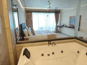a bathroom with a tub and a bed in a mirror at Nisarga Lake Resort Tapola in Satara