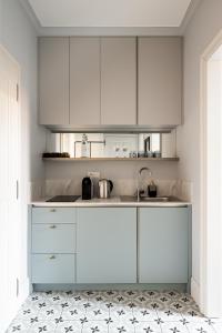 a kitchen with white cabinets and a tile floor at Moja Apartments Krakow Old Town in Krakow