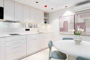a kitchen with white cabinets and a white table and chairs at iloftmalaga Puerto in Málaga