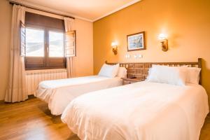 dwa łóżka w pokoju hotelowym z oknem w obiekcie Hostal Gran Duque w mieście Piedrahita