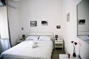 una camera bianca con un letto bianco e due tavoli di Affittacamere Porta Del Vento a Caltagirone