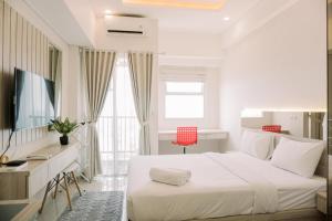 a white bedroom with a bed and a desk at Simply Look Studio at Parkland Avenue Apartment By Travelio in Tangerang +9 photos