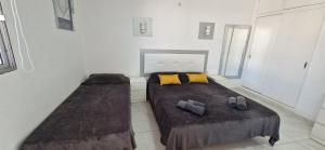 deux lits dans une chambre blanche avec des oreillers jaunes dans l'établissement sweet dreams, à Costa del Silencio