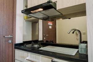 a kitchen with a stove and a sink with a mirror at Simply Look Studio at Parkland Avenue Apartment By Travelio in Tangerang