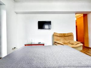 a bedroom with a bed and a chair and a television at 05 Апартаменты в центре города - выбор для туриста и деловых поездок in Almaty