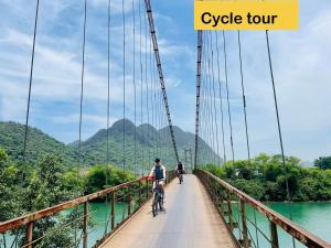 a bridge over a river with two people riding bikes on it at TuTu's Homestay Phong Nha in Phong Nha