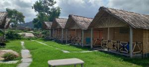 una fila de cabañas de madera en un campo de hierba en Shanthi Dhama Hampi, en New Hampi