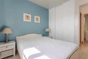 een slaapkamer met een wit bed en een blauwe muur bij Maison N°3 - Résidence Pingettes in Le Bois-Plage-en-Ré +22 foto's