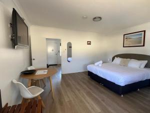 ein Schlafzimmer mit einem Bett, einem Schreibtisch und einem Tisch in der Unterkunft Clearwater Motel Apartments in Esperance