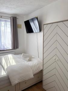 ein Schlafzimmer mit einem Bett und einem Fernseher an der Wand in der Unterkunft Modern 3 Bed Free Parking 10 mins walk to station in Dagenham