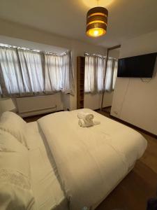 ein Schlafzimmer mit einem weißen Bett und einem Handtuch darauf in der Unterkunft Modern 3 Bed Free Parking 10 mins walk to station in Dagenham