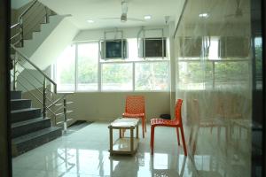 drie stoelen en een tafel in een kamer met een trap bij S M Residency in Tiruppūr
