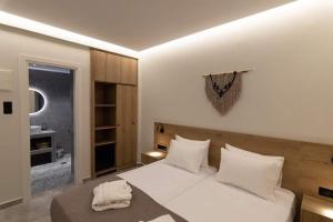 a bedroom with a large white bed with white pillows at VASILAS Luxury Rooms & Suites in Agios Georgios