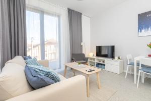 a white living room with a couch and a table at EURÓPA Apartments in Dunajská Streda
