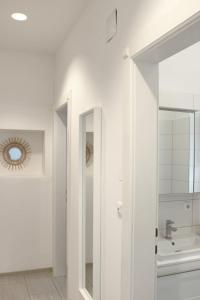a white bathroom with a sink and a mirror at Apartment Two am Stadtpark in Villach
