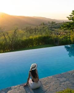 a woman sitting on the edge of a swimming pool at Il Casolese, Private Pool, Nature, Greve In Chianti in Greve in Chianti