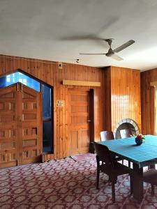 a dining room with a blue table and wooden walls at The Bilt farmhouse in Srinagar