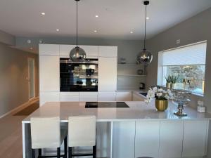 Una cocina con gabinetes blancos y sillas blancas. en Leilighet med høy standard og fantastisk havutsikt, en Kabelvåg