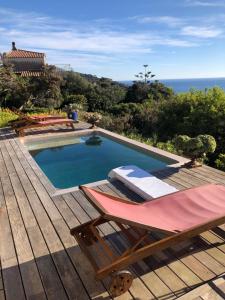a swimming pool with a deck and chairs and the ocean at Villa Mirabel in Île du Levant