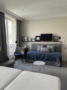a living room with a bed and a tv at Hôtel Londres et New York - Teritoria in Paris