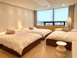 a bedroom with two beds and a large window at NewsenseB-1sec from Hongdae Sub&wifi in Seoul