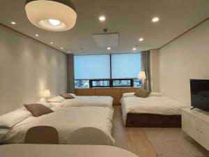 a bedroom with three beds and a flat screen tv at NewsenseB-1sec from Hongdae Sub&wifi in Seoul