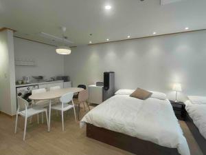 a bedroom with a bed and a table and a kitchen at NewsenseB-1sec from Hongdae Sub&wifi in Seoul