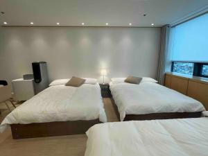 a bedroom with three beds and a window at NewsenseB-1sec from Hongdae Sub&wifi in Seoul