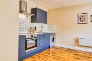 a kitchen with blue cabinets and a washer and dryer at Spacious City Center 2 Bed Apartment Free Wifi in Lincoln +5 photos