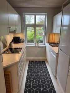 a kitchen with white cabinets and a window at Garden Apartment by the Sea in Sønderborg +24 photos