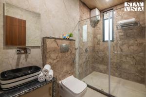 a bathroom with a shower and a toilet at StayVista at The Binclave with Jacuzzi, Pvt Indoor Pool, Bar & Projector in Jaipur +12 photos