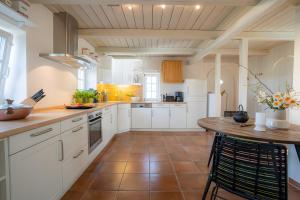 a large kitchen with white cabinets and a wooden table at Landhaus Sommerland in Uelvesbüll