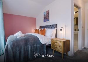 a bedroom with a bed and a wooden night stand at Modern 5 Bedroom House in Manchester by PureStay - Short Stay with Service Accommodation & Free Parking in Manchester