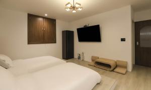 a bedroom with a white bed and a flat screen tv at Hotel Gongsan in Gongju