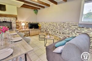 a living room with a couch and a stone wall at Du bonheur a la campagne in Mauron