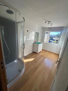 a bathroom with a glass shower and a wooden floor at La forge in Laroque-de-Fa