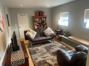 a living room with a couch and chairs and a table at Cove side Bliss in Whangaparaoa