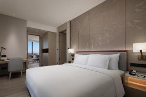 a bedroom with a large white bed and a desk at Wanda Jin Xiaohe Xincheng in Taiyuan