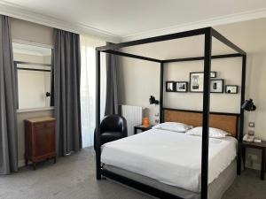 a bedroom with a black canopy bed and a chair at Hôtel Londres et New York - Teritoria in Paris