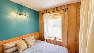 a bedroom with a bed with a blue wall and a window at aTelpa Namiņš Latgalē in Adamova