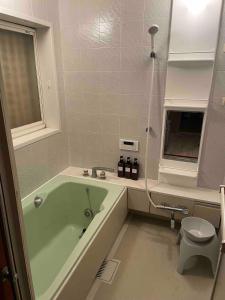 a bathroom with a green tub and a toilet at 2-minute walk to the sea, a secret base that children can also enjoy, beautiful high-ceiling beams, free gas BBQ rental, detached villa in Kujukuri