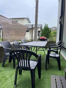 a patio with a table and chairs on the grass at 2-minute walk to the sea, a secret base that children can also enjoy, beautiful high-ceiling beams, free gas BBQ rental, detached villa in Kujukuri
