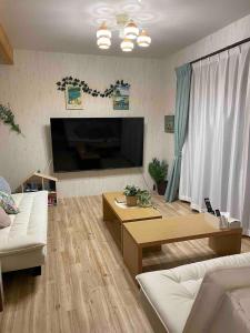 a living room with a large flat screen tv at 2-minute walk to the sea, a secret base that children can also enjoy, beautiful high-ceiling beams, free gas BBQ rental, detached villa in Kujukuri