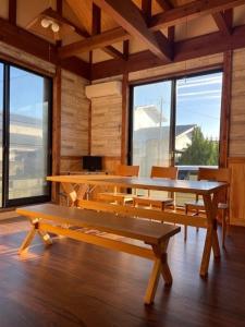 a dining room with tables and chairs and windows at 2-minute walk to the sea, a secret base that children can also enjoy, beautiful high-ceiling beams, free gas BBQ rental, detached villa in Kujukuri