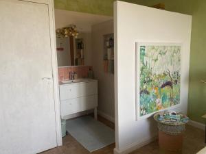 a bathroom with a sink and a painting on the wall at Le Rucher des Arts in Alba-la-Romaine +29 photos
