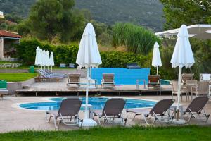 a pool with chairs and umbrellas next to a pool at Thesmos Village in Mitika