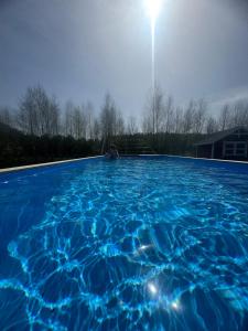 a person is sitting in a swimming pool at Luxury Villa in Liva Park - dostęp do basenu, całoroczne jacuzzi, grill, prywatny ogrodzony teren in Liwa