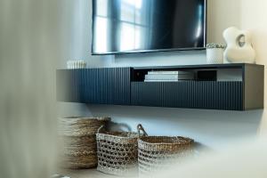 a bathroom with two baskets and a television on a wall at Oskar Apartments in Neustift im Stubaital