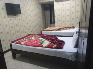 two twin beds in a room with a tv at Star Residency Hotel in Islamabad